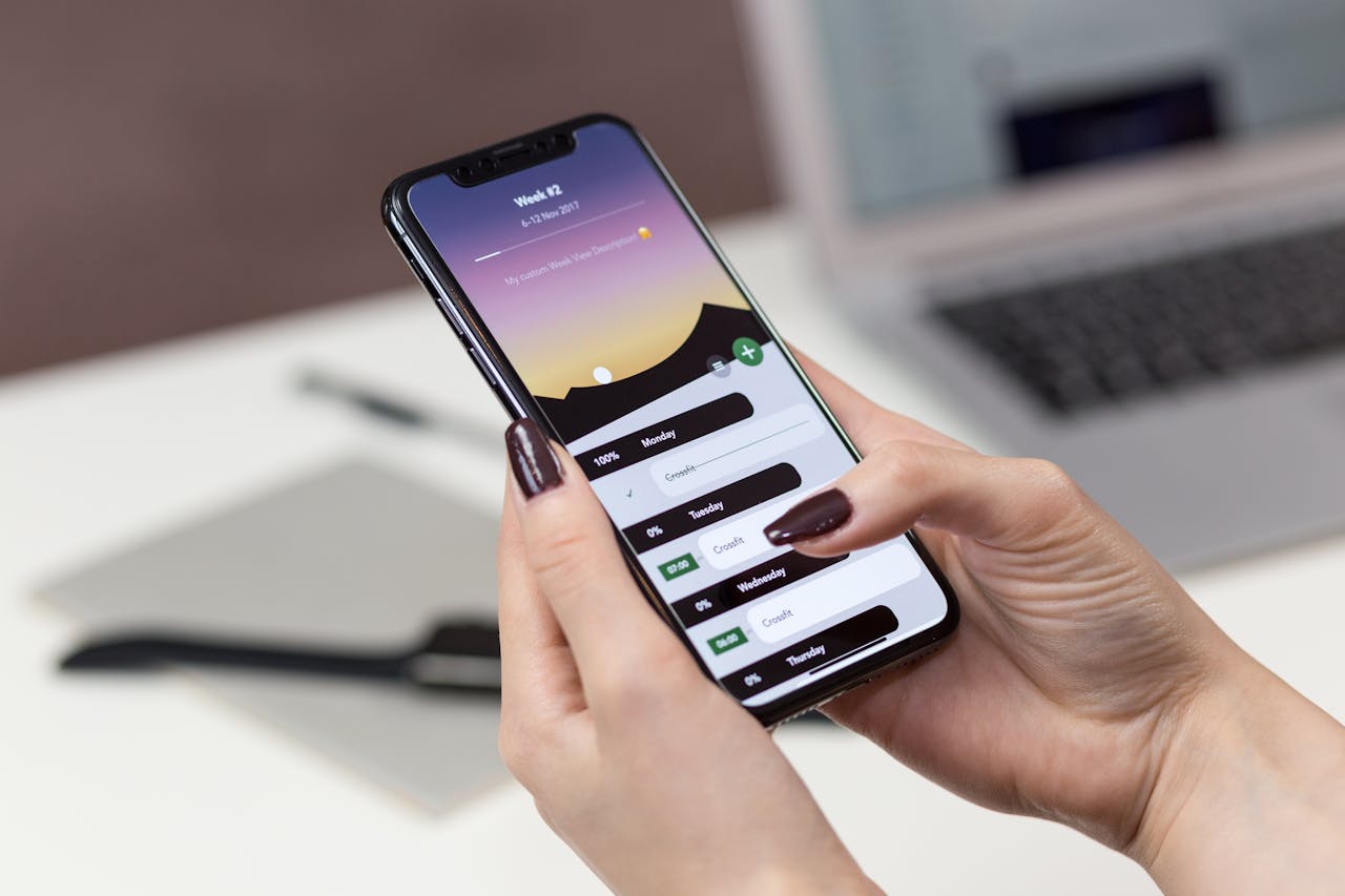 A woman interacts with a productivity app on her smartphone at a desk setup.